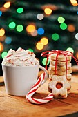 A cappuccino with cream, a candy cane and a stack of biscuits