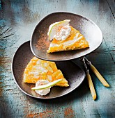 Two slices of pear tart with cream on a plate