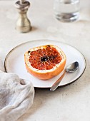 A baked caramelised grapefruit half on a plate