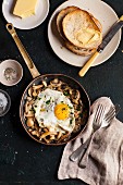 Fried mushrooms with a fried egg in a pan served with toast and butter