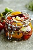 Pickled tomatoes with herbs and cinnamon in a preserving jar