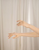 Woman's hands in front of white curtain
