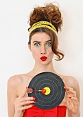 Young woman holding target with dart stuck in tomato