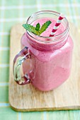 A berry smoothie with banana in a tankard with a straw