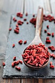 Goji berries on a wooden spoon and a slate surface