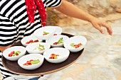 Bowls of mozzarella, tomato and basil being carried on a tray