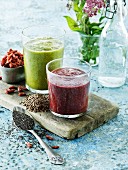 Two vegetable smoothies and ingredients on a wooden board