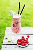 A summer raspberry cocktail on a garden table