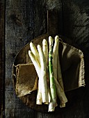 White and green asparagus on a rustic wooden paddle