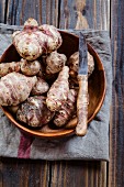 Jerusalem artichokes in a wooden bowl with a knife