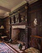 Elegant, antique fireplace with carved wooden surround on wood-panelled wall