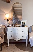 Table lamp and mirror on antique white chest of drawers