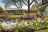 Pond, seating area and greenhouse in spring garden