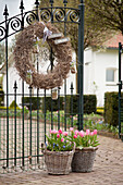 Wreath on wrought iron gate and baskets of spring flowers