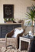 Wicker armchair and side table in front of white brick wall