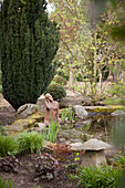 Sculpture in garden pond next to yew tree