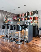 Bar stools with black leather seats in front of mirrored counter in open-plan home bar