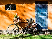 Basket of wildflowers on bicycle leaning against cottage wall