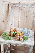 Lit candles in candle holders made from pine cone bundles tied with checked ribbons