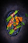 Asparagus and carrots wrapped in bacon with vegetable crisps