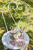 Posies on crocheted coasters on white metal chair in garden