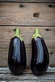 Two aubergines on a wooden surface