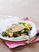Chicken breast with potatoes, peas and baby corn on parchment paper