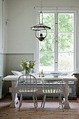 Pale grey chairs and vintage table in dining area below lattice window