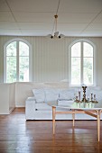 Round coffee table in front of white sofa and arched windows