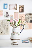 Vintage-Krugvase mit floralem Muster und Rosenknospen vor nostalgischen Postkarten und Zeitschriftenauschnitten