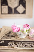 Pale pink ranunculus buds in vintage bowl on top of old magazines