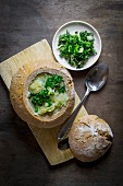 Potato soup served in hollowed out bread garnished with fresh herbs