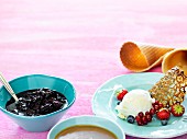 Vanilla ice cream with berries and a liquorice wafer served with ice cream cones, berries and caramel sauce