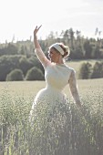 A young bride waving in an oat field