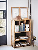 Books and framed pictures on vintage wooden shelves next to fishing rod leant against wall in corner