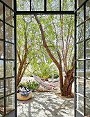 View of woman lying in hammock on terrace seen through open double doors