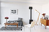 Coffee table on black-and-white-striped rug, chaise longue and white chair in minimalist living room