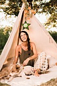 Lachende Frau mit Hund in geschmücktem Tipi-Zelt