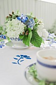 Blau-weiss dekorierter Kaffeetisch mit Sommerblumen