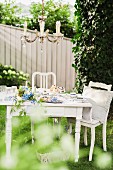 Chandelier above romantic coffee table set with blue flowers in garden