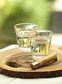Glasses of white wine and a corkscrew on a wooden board