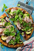 Pizza with courgette, rocket and ham, halved