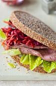 A roast beef sandwich, coleslaw and lettuce