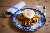 A slice of toast topped with tomatoes, chard, chickpeas and a heart-shaped fried egg