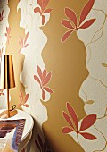 Wall decorated with cut-out sections of floral wallpaper over beige paint (detail)