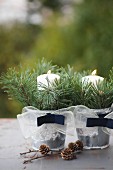 Zwei Zinkeimer mit Schleifen, Fichtenzweigen und brennenden Kerzen dekoriert, davor Lärchenzapfen