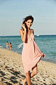 Junge Frau in rosa Sommerkleid am Strand