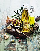 An arrangement of oils with olive sprigs, olives and bread