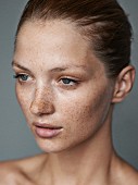 A close-up portrait of a young woman with lots of freckles