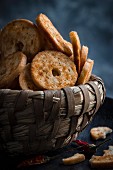 Bread chips in a bread basket with chillis against a dark background